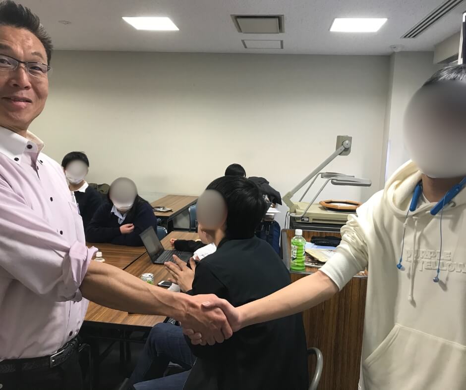 生徒と固い握手を交わす